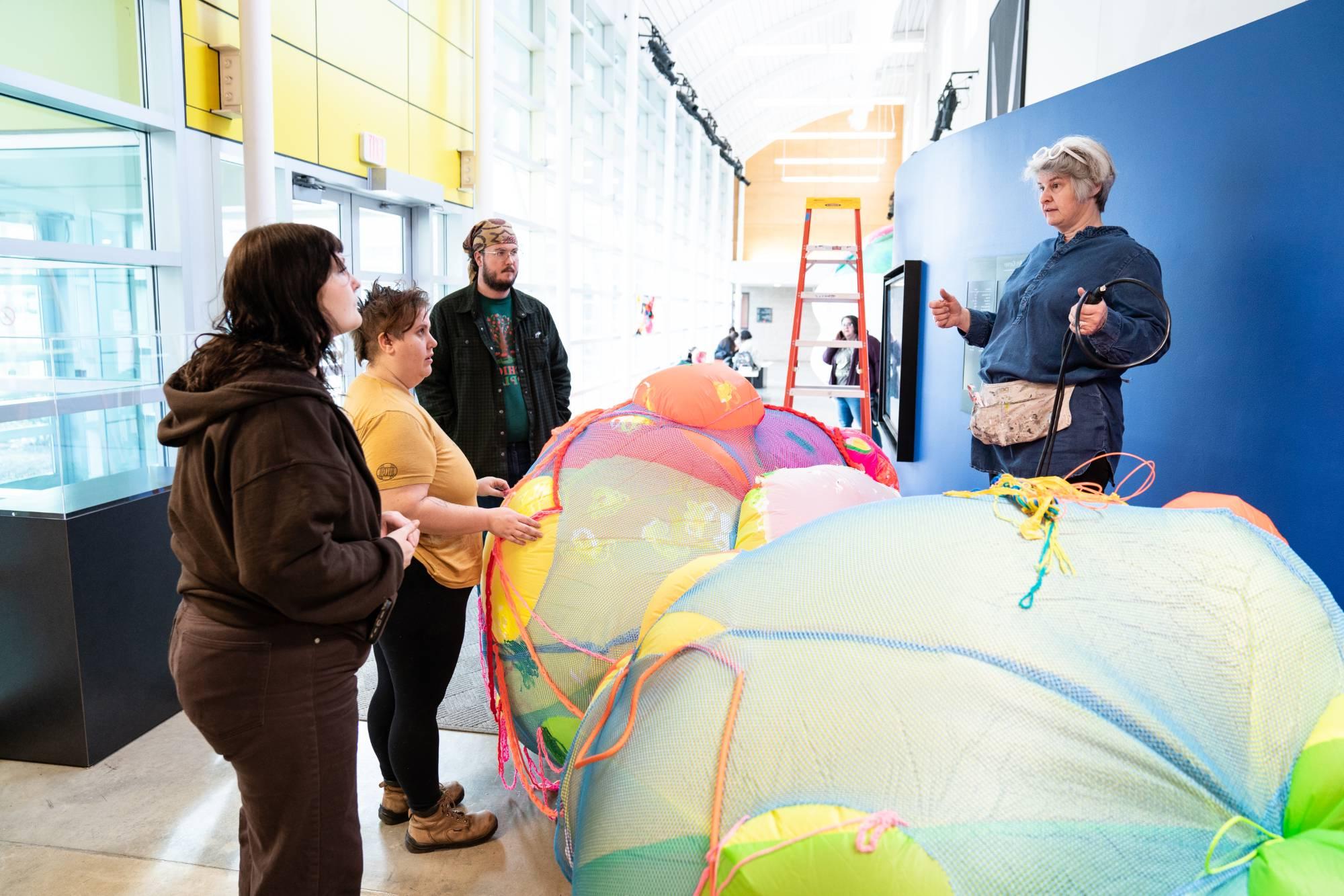 Brightly colored ball shaped sculpture being installed by group of students & artist Claire Ashley.